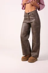 Pantalón de corte recto y holgado confeccionado en eco cuero con acabado texturizado. Presenta diseño de cinco bolsillos, cierre frontal y costuras reforzadas en los laterales.