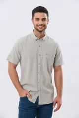 Camisa de manga corta confeccionada en mezcla de lino y algodón, con estampado de cuadros pequeños en tonos azules. Presenta cuello camisero con botones, cierre frontal abotonado, bolsillo aplicado en el pecho y dobladillo redondeado.
