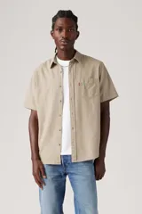Camisa de manga corta color beige con bolsillo en el pecho y cierre con botones.