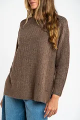 Sweater de punto texturado en color beige, con cuello redondo y mangas largas. Presenta un diseño de tejido acanalado vertical y corte holgado.