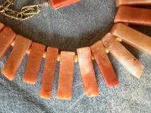 Collar de cuarzo natural en tonos terracota y coral, con cuentas rectangulares y cadena dorada ajustable con cierre de mosquetón.