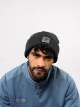 Gorro de lana Umbro, modelo Altiplane, de tejido acanalado en color gris oscuro con parche frontal de goma con el logo de la marca.