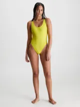 Malla enteriza Calvin Klein de textura acanalada brillante, color amarillo neón. Presenta cuello redondo, espalda amplia y tirantes elásticos negros con el logo de la marca. Incluye copas moldeadas suaves con relleno extraíble.