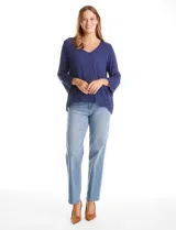 Blusa azul de escote en V y manga larga con terminación amplia. Presenta detalles de bordado y calados tanto en las mangas como en el ruedo delantero.