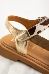 Sandalia de cuero color dorado con tiras marrón y estampado animal print, con plataforma marrón.