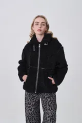 Campera de corderito color negro, con cuello alto y cierre frontal completo. Presenta detalles de vivos en cuero sintético en el cierre, bolsillos y costuras, además de una hebilla decorativa en el cuello.