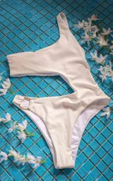 Traje de baño enterizo blanco con un solo hombro y aro dorado en la cadera.