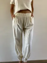 Pantalón de lino color manteca, de corte holgado con cintura elástica y puños elásticos en los tobillos. Cuenta con bolsillos laterales.
