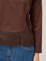 Remera de manga larga en color marrón, confeccionada en una combinación de tejido de punto y tela plana. Presenta un diseño de superposición frontal con costura decorativa en contraste y un panel inferior de textura diferenciada.