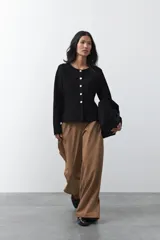 Cardigan negro de tejido de punto con cuello redondo y cierre frontal con botones a contraste. Presenta un corte entallado en la cintura con una silueta levemente evasé y mangas largas.