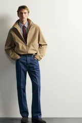 Jeans de denim azul oscuro sin lavados, corte recto con raya frontal planchada, tiro medio, cinco bolsillos y cierre frontal de botonadura. Colección especial Aaron Levine x Zara.