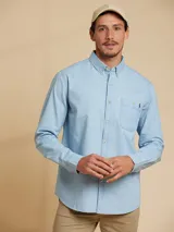 Camisa celeste de manga larga con cuello abotonado y bolsillo en el pecho.