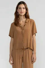 Camisa color marrón de manga corta en crepé de viscosa suave, con cuello camisero y detalle de flor en la botonadura central.