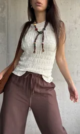 Blusa de punto sin mangas en color natural, con textura fruncida en todo el diseño y cuello redondo.