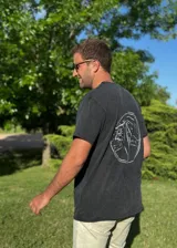 Remera negra de manga corta con cuello redondo y estampado circular en la espalda con motivos de playa y montaña en color blanco.