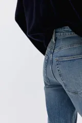 Jean de tiro alto con corte acampanado desde la rodilla y bajo deshilachado. Presenta diseño clásico de cinco bolsillos, cierre frontal con botón y costuras reforzadas en el ruedo.
