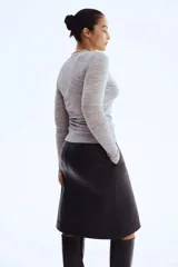 Pollera tubo de largo midi, color negro, confeccionada en material con textura de cuero. Presenta bolsillos al bies y una abertura frontal en el bajo.