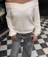 Sweater de punto color negro, con escote estilo bardot y mangas largas. Presenta un diseño acanalado y corte ajustado.