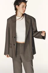 Blazer oversize de Zara con diseño a rayas verticales, cuello con solapa de muesca y hombreras. Presenta un cierre frontal cruzado con doble botonadura, bolsillos delanteros con solapa y un bolsillo de vivo en el pecho. Incluye forro interior a tono.
