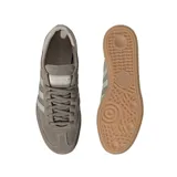Championes adidas Handball Spezial inspirados en el modelo de 1979, confeccionados en gamuza gris topo con las clásicas tres tiras y refuerzo de talón en tono claro, inscripción lateral en letras doradas y suela de goma de tipo caramelo.