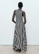 Vestido largo de punto fino con diseño a rayas verticales en blanco y negro, sin mangas, con cuello redondo y corte evasé.