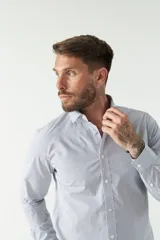 Camisa de manga larga para hombre, color azul claro con microestampado de cuadros. Presenta un corte slim y cuello abotonado.