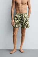 Bañador de hombre de largo medio, con estampado de cebra en tonos amarillo claro y negro/marrón oscuro. Presenta cintura elástica ajustable con cordón negro, bolsillos laterales y un bolsillo trasero de vivo.