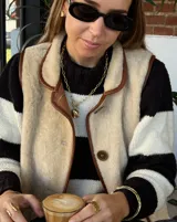 Collar de cadena de eslabones alargados con cierre frontal tipo T y dije circular de textura rústica e irregular.