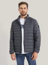 Chaqueta acolchada gris de poliamida con cuello alto, cierre de cremallera, dos bolsillos delanteros con cremallera y logo de Tommy Hilfiger bordado en el pecho.