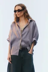 Camisa oversize blanca de lino, con corte cuadrado, mangas raglán cortas con puños anchos, aberturas laterales y cierre frontal de botones.