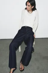 Pantalón de tiro alto con pernera recta, confeccionado en denim oscuro. Presenta nervios marcados en el delantero, bolsillos frontales tipo parche y cierre frontal con cremallera y botón.