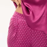 Conjunto de pijama de dos piezas color fucsia, compuesto por un top de tirantes con encaje en el escote y un pantalón largo con estampado geométrico.