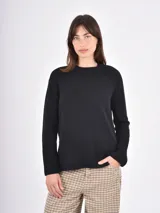 Buzo de tejido de punto color negro, con cuello redondo, mangas largas y puños anchos acanalados. Presenta un diseño con ruedo asimétrico y aberturas laterales.