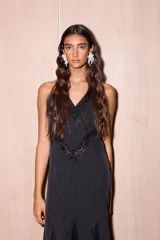 Vestido largo negro con estampado de lunares blancos, confeccionado en jersey con lurex y encaje. Presenta escote en V profundo, tirantes finos y detalles de encaje en el pecho y el ruedo.