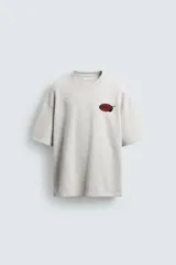 Sudadera gris de corte relaxed fit, cuello redondo y manga corta. Presenta un estampado en el pecho con la frase "Tokyo Kitchen" en un óvalo rojo con palillos.