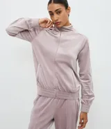 Campera deportiva de plush color negro con cuello alto, cierre frontal por cremallera, bolsillos laterales y detalle de piping blanco contrastante en mangas y bolsillos.