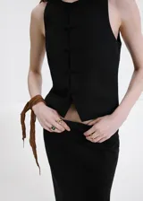 Chaleco negro de mezcla de lino y algodón, con cuello redondo, sin mangas y cierre delantero de botones alamares.