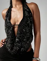 Top halter negro con escote profundo, aplicaciones de lentejuelas y espalda descubierta.
