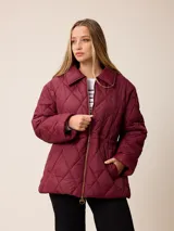 Campera acolchada de diseño matelassé con patrón de rombos, color bordó. Presenta cuello camisero, cierre frontal con cremallera metálica, cintura entallada con elástico y bolsillos laterales. Incluye un pequeño bordado distintivo en el pecho.