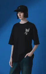Remera de manga corta y cuello redondo con calce oversize. Presenta una estampa frontal en color crema con diseño artístico de un ángel y una rosa, acompañada de frases en español. Confeccionada en algodón premium.