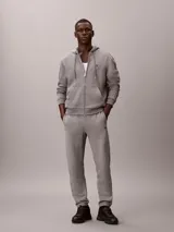 Pantalón jogger gris melange de felpa Calvin Klein, con cintura elástica, bolsillos laterales y puños acanalados. Cuenta con el monograma CK bordado discretamente en la pierna.