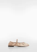 Zapato tipo bailarina color rosa pálido, de tejido satinado, con punta redonda, lazo decorativo y tira elástica sobre el empeine.
