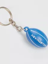 Llavero Kevingston con dije de pelota de rugby azul, argolla metálica y cadena de eslabones plateados.
