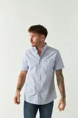 Camisa de manga corta con estampado de cuadros vichy en azul y blanco. Presenta cuello con botones, cierre frontal con botones y logo bordado en el pecho.