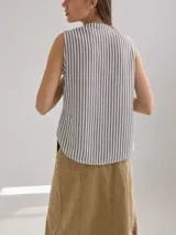 Camisa sin mangas a rayas verticales color beige y blanco, con cuello mao y cierre frontal con botones.