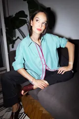 Camisa verde con rayas verticales blancas y detalles de zigzag rosa en el frente.