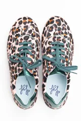 Zapatillas de estilo running con estampado animal print de leopardo sobre fondo rosado. Presentan detalles en color verde botella en la lengüeta, cordones, collarín y talón. Cuentan con suela de goma dentada y cuña interna oculta para mayor comodidad.