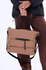 Bolso tipo tote color negro, con diseño acolchado y manijas fijas. Cuenta con una correa larga ajustable y desmontable, cierre principal superior y un bolsillo frontal con cierre.