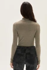 Polera de manga larga con cuello alto, confeccionada en tejido de punto acanalado con diseño de rayas horizontales en color marrón y turquesa. Presenta un bordado pequeño en el pecho y un calce ajustado al cuerpo.
