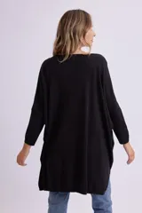 Buzo de punto oversize color negro, con cuello redondo, mangas largas y dobladillo asimétrico más largo en la parte trasera.